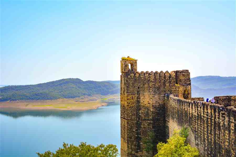 Stone fortress wall meeting a quiet lakeside view