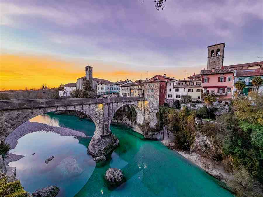 Historic stone bridge over turquoise water at sunset