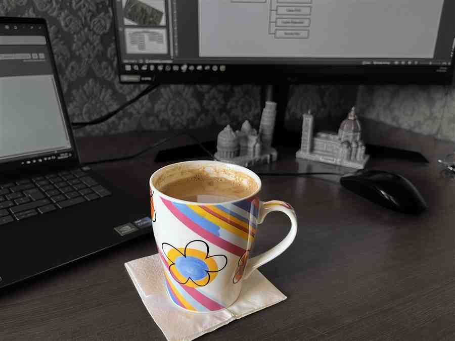 Colorful coffee mug on a desk between computer screens