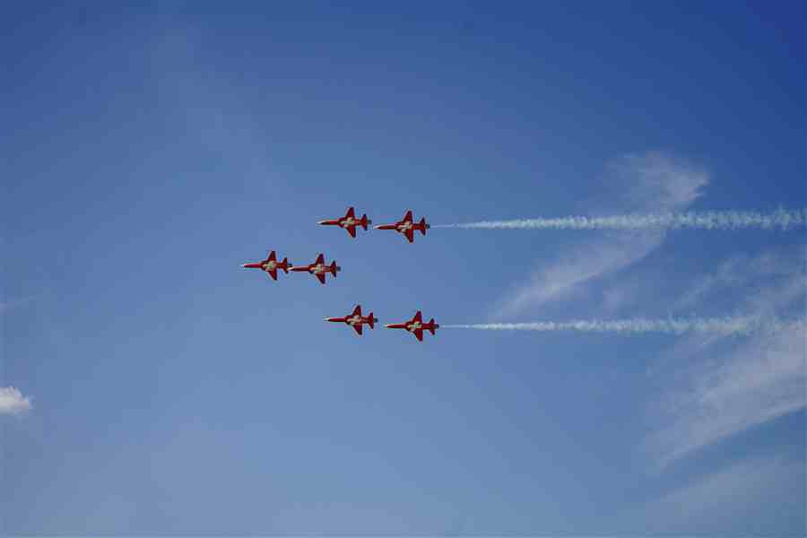 Red aerobatic jets flying in formation with white trails